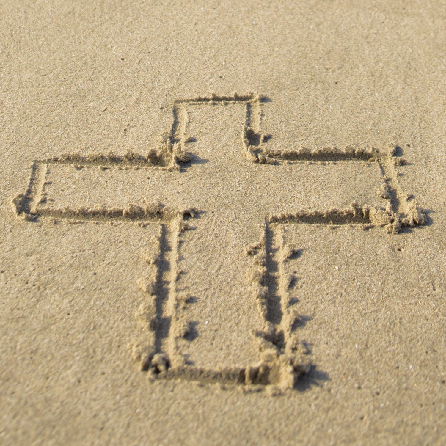 cross drawn in sand